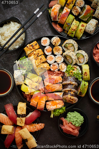 Image of Assorted sushi set served on dark dark background. Top view of seafood, various maki rolls