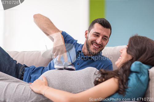 Image of young pregnant couple relaxing on sofa