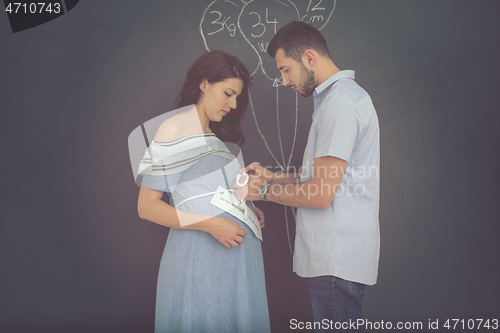 Image of pregnant couple drawing their imaginations on chalk board