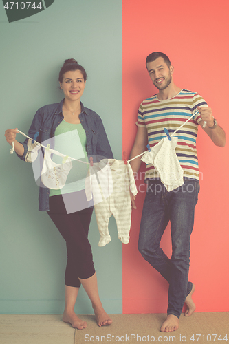 Image of young couple holding baby bodysuits