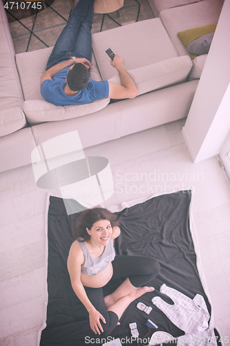 Image of top view of pregnant woman checking list of baby clothes