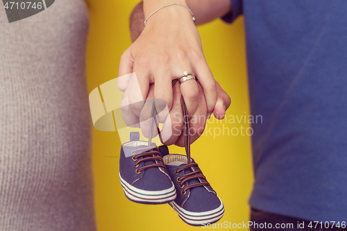 Image of couple holding newborn baby shoes