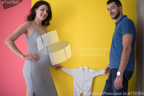 Image of young couple holding baby bodysuits