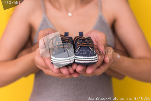 Image of couple holding newborn baby shoes