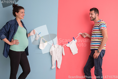 Image of young couple holding baby bodysuits