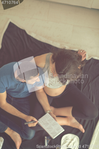 Image of top view of couple checking a list of things for their unborn ba