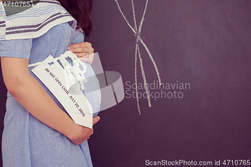 Image of Portrait of pregnant woman in front of black chalkboard