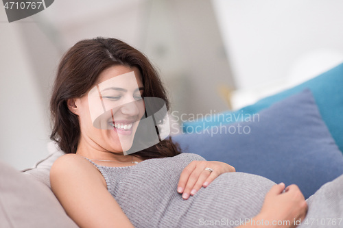 Image of pregnant woman sitting on sofa at home