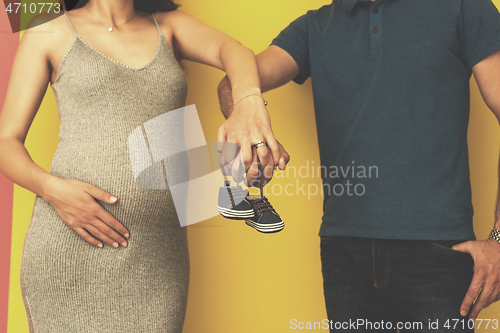 Image of couple holding newborn baby shoes