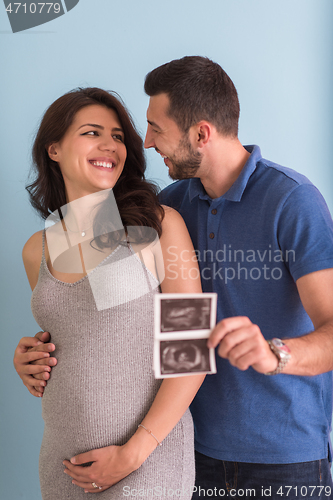 Image of couple looking ultrasound picture isolated on blue background