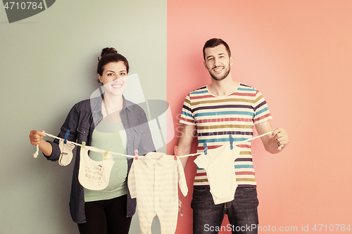 Image of young couple holding baby bodysuits