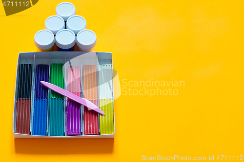 Image of There are jars of gouache above the plasticine box, yellow background