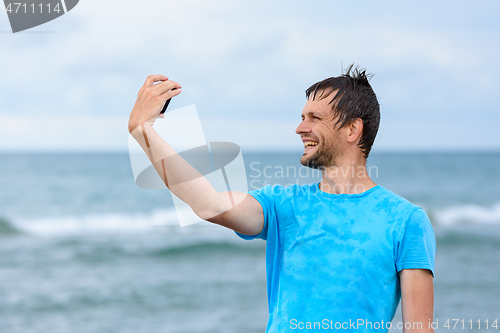 Image of A man on vacation takes pictures of himself on a mobile phone