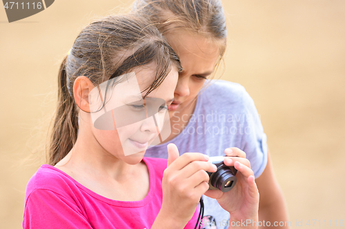 Image of Two girls watching photos on the screen of a digital camera