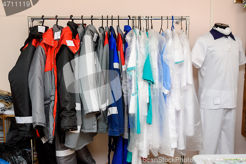 Image of Sewn clothes hang on a large pipe hanger in a sewing workshop