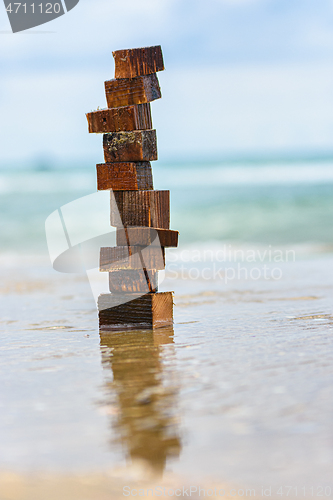 Image of A tower made of wet pieces of wood stands on the wave-laden seashore