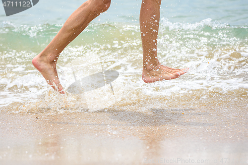 Image of Funny feet running along the beach splashing sea water