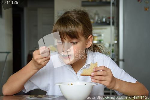 Image of Girl at home eating soup from a white bowl at the dinner table