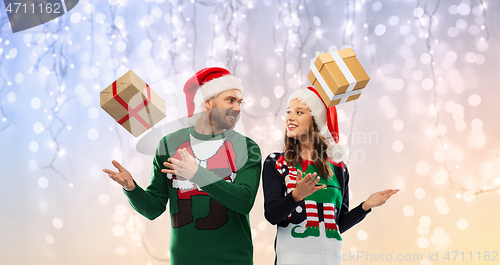 Image of happy couple in christmas sweaters with gifts