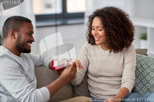 Image of african american man giving woman engagement ring