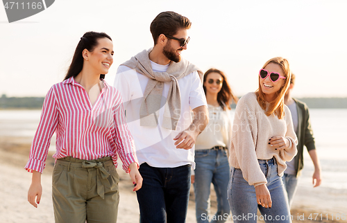 Image of happy friends walking along summer beach