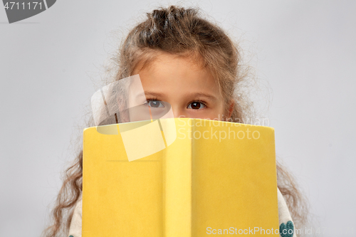 Image of little girl hiding behind yellow book