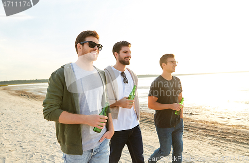 Image of young men with non alcoholic beer walking on beach