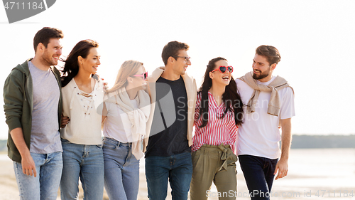 Image of happy friends walking along summer beach