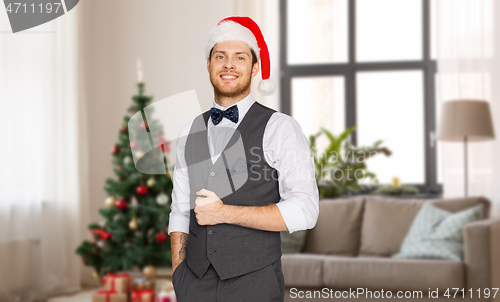 Image of happy man in santa hat and suit at christmas