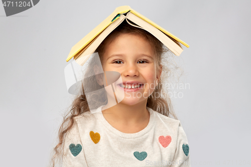 Image of portrait of smiling girl with book on head