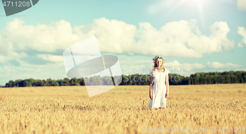 Image of happy young woman in flower wreath on cereal field