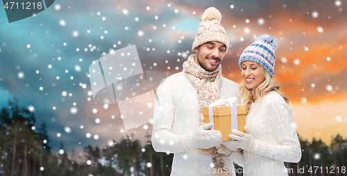 Image of smiling couple in winter clothes with gift box