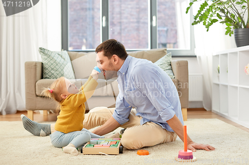 Image of father playing with little baby daughter at home