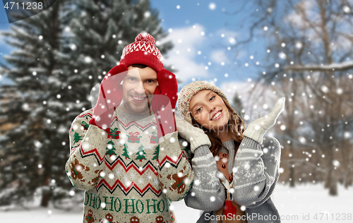 Image of happy couple in ugly christmas sweaters in winter