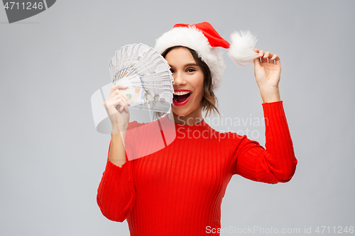 Image of happy woman in santa hat with money on christmas
