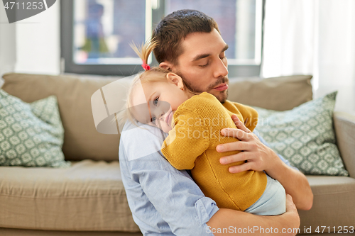 Image of loving father holding baby daughter at home