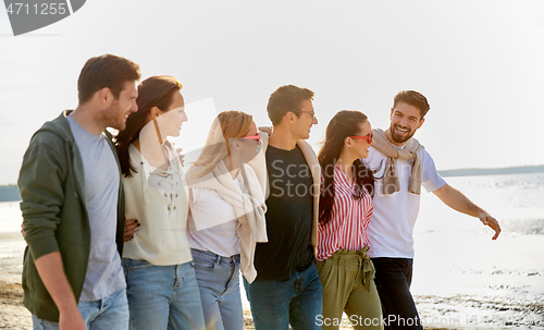 Image of happy friends walking along summer beach