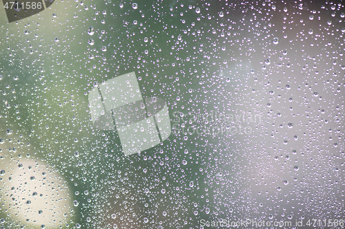 Image of Drops of rain on window with abstract lights