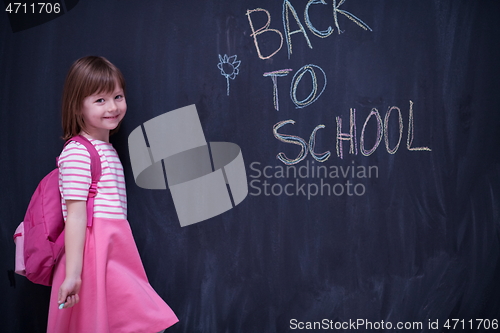 Image of school girl child with backpack writing  chalkboard