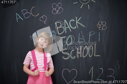 Image of school girl child with backpack writing  chalkboard