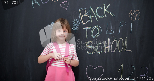 Image of school girl child with backpack writing  chalkboard