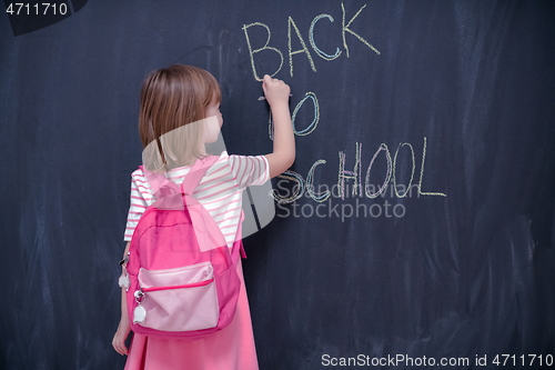 Image of school girl child with backpack writing  chalkboard