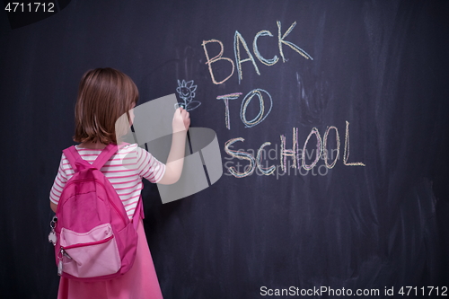 Image of school girl child with backpack writing  chalkboard