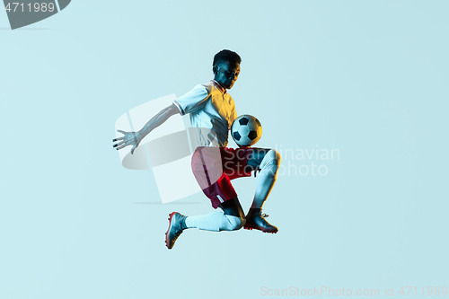 Image of Male soccer player kicking ball in jump isolated on gradient background