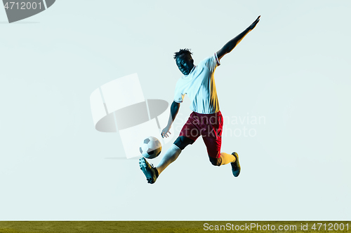 Image of Male soccer player kicking ball isolated on white background