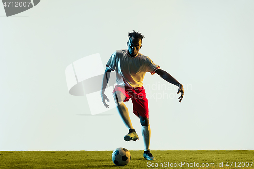 Image of Male soccer player kicking ball isolated on white background