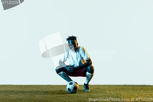 Image of Male soccer player sitting with the ball isolated on white background