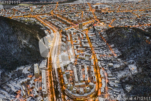 Image of Aerial view of city and mountain behind at dusk