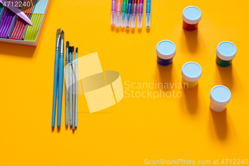 Image of Stationery, plasticine, brushes, gouache and felt-tip pens lie on an orange background