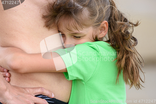 Image of Happy girl hugs the belly of an adult